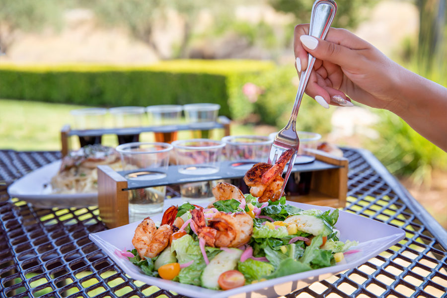 woman dining on shrimp salad with tasting flight of wine