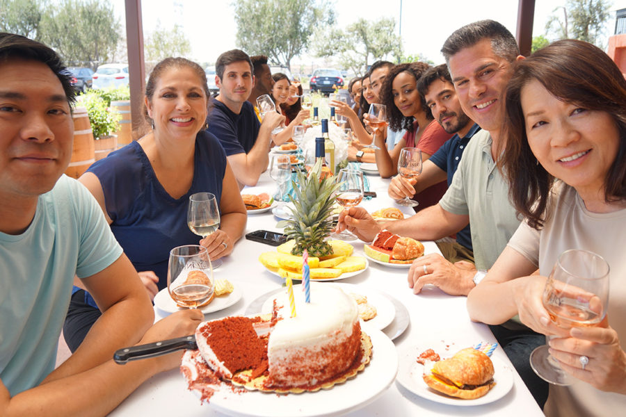 Large group of wine drinkers celebrating with birthday cake